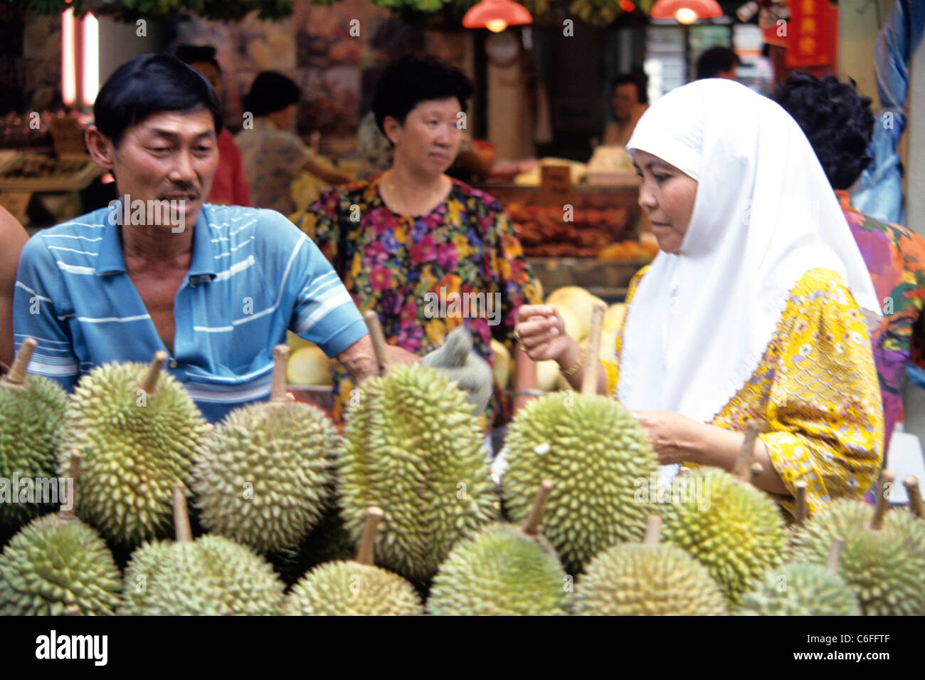 Donna musulmana in burqa shopping per durians nel mercato di Singapore Foto Stock