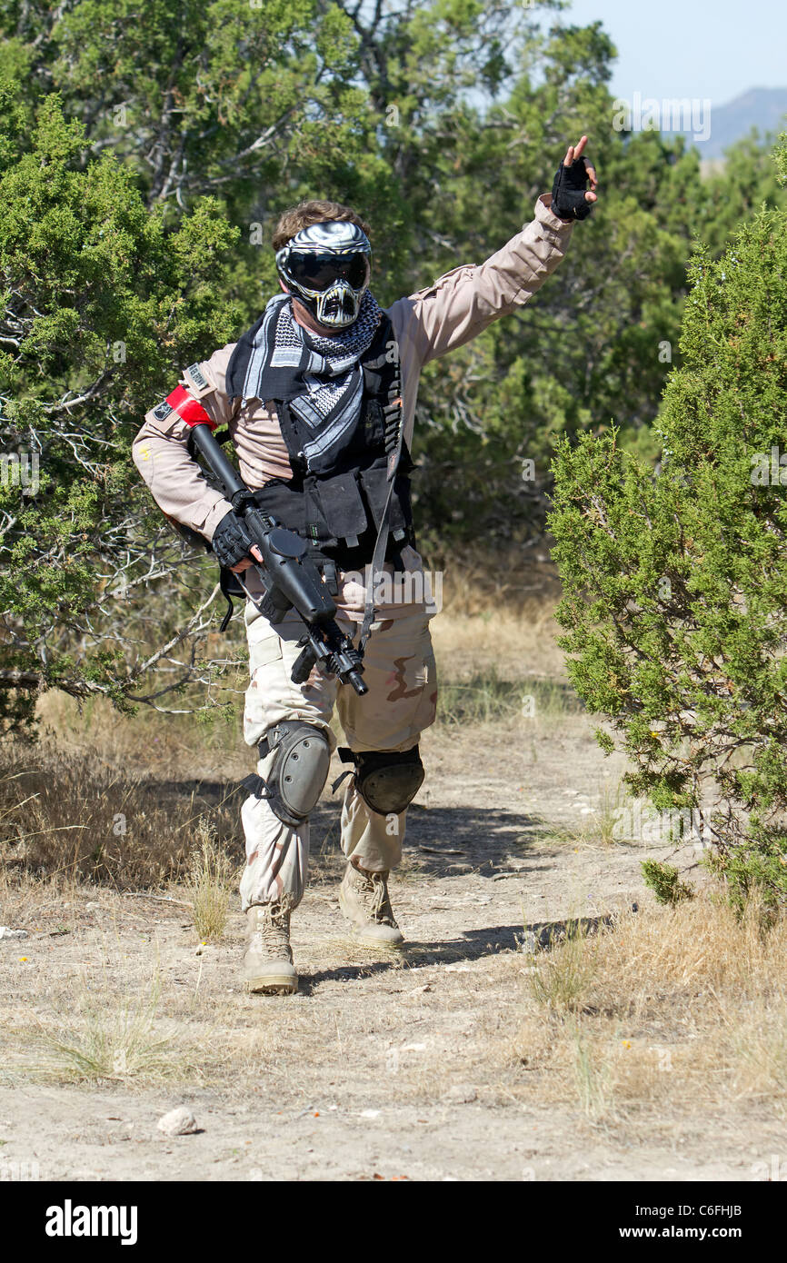 Il paintball tiratori da un albero di scatto a posizione di nemico e soldati. Dare ordini ad altri compagni di squadra. Piena protezione individuale. Foto Stock