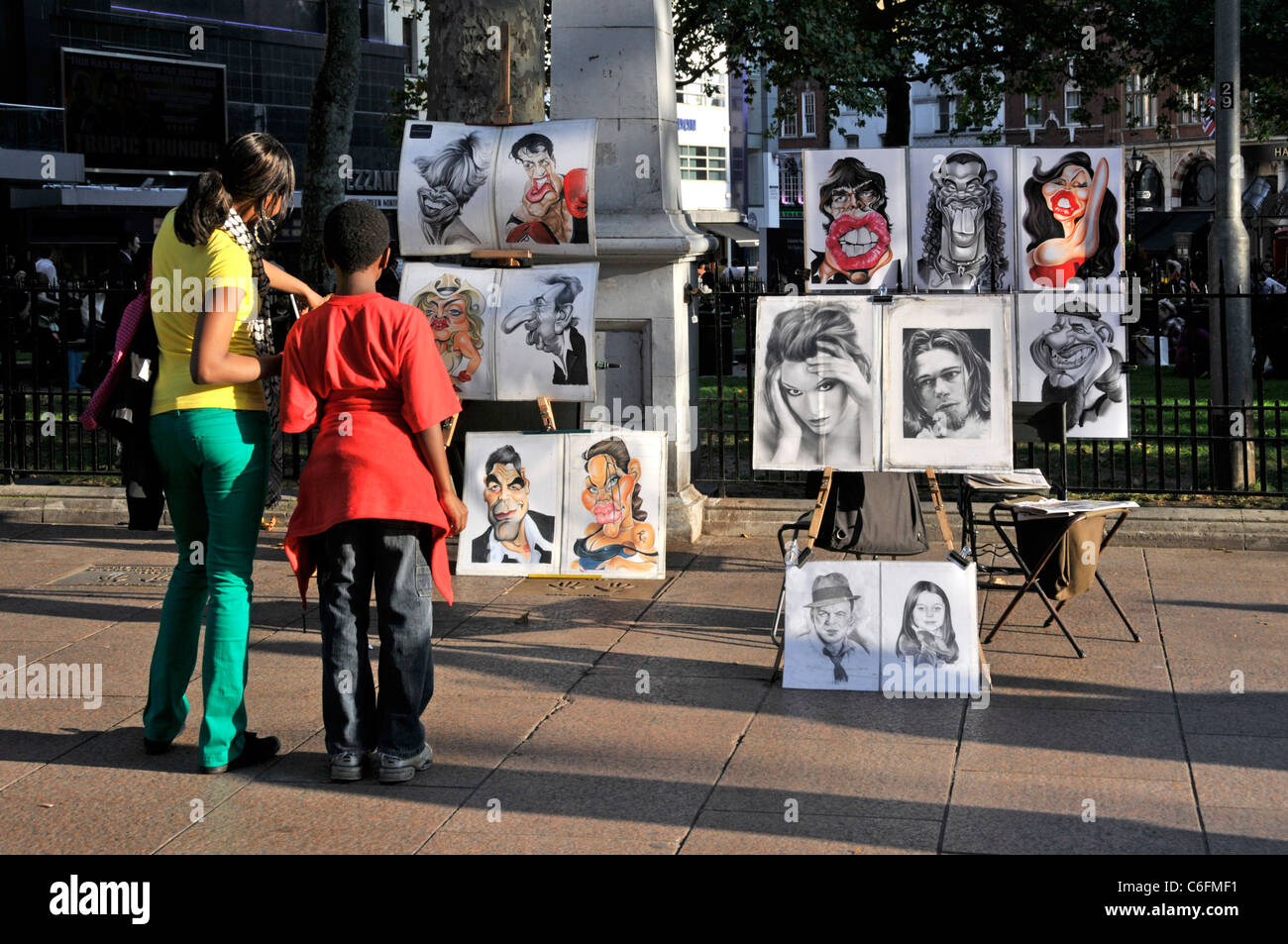 Londra summer street scene vista posteriore di coloro che visualizzano la caricatura illustrazione ritratto bozzetti nella soleggiata Leicester Square London West End England Regno Unito Foto Stock