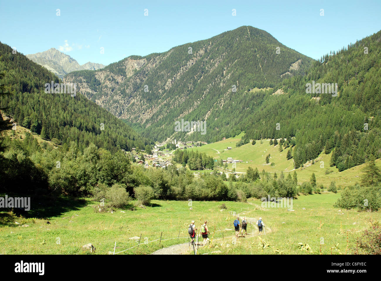 Walkers seguire un buon percorso attraverso una valle nelle Alpi francesi vicino a Mont Blanc con alte montagne sullo sfondo Foto Stock