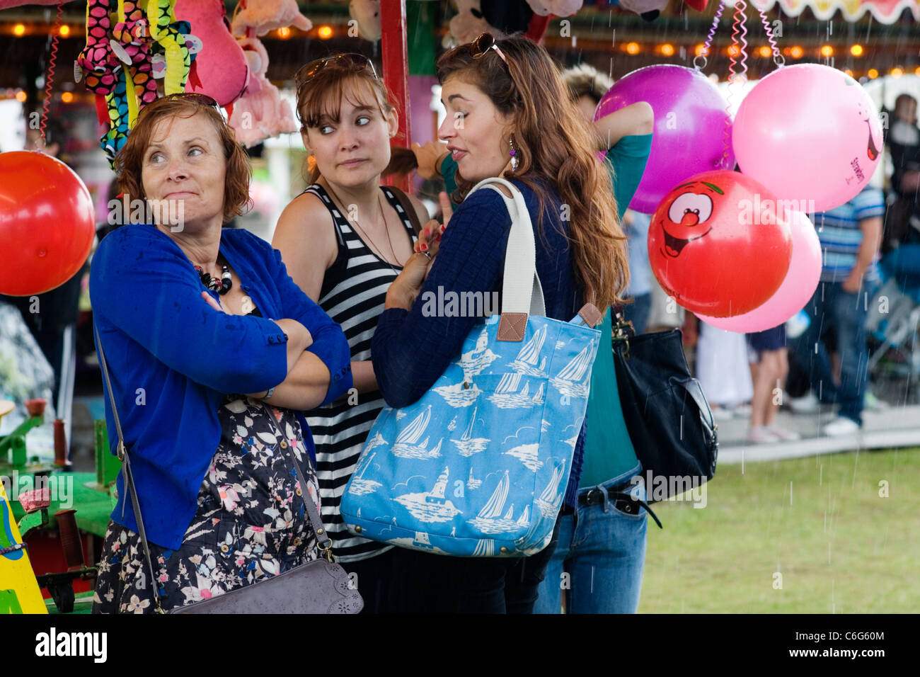 La madre e le figlie di prendere rifugio dal rovescio di pioggia a Southsea kite festival Foto Stock