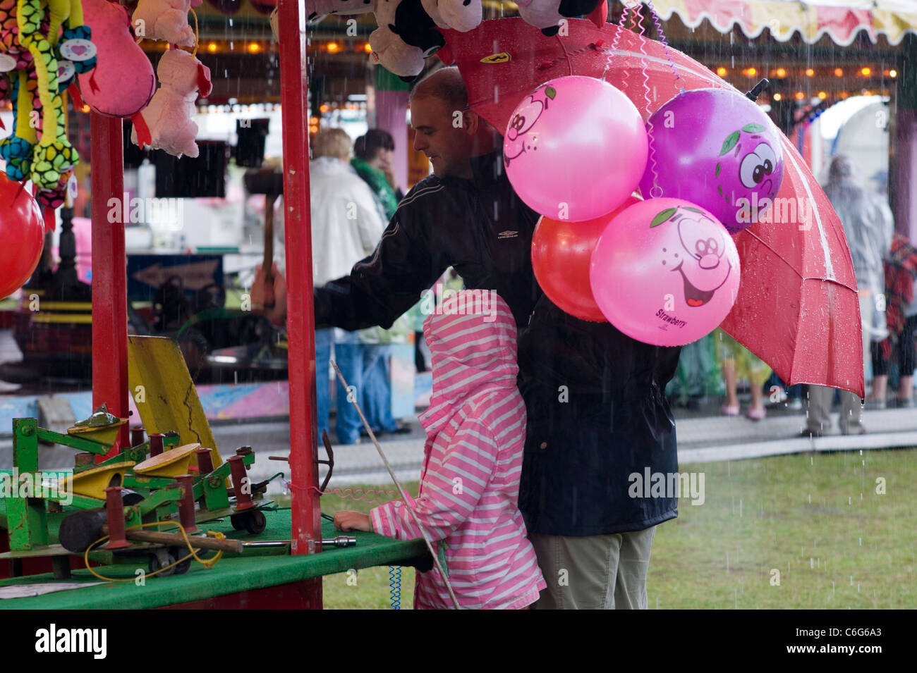 Padre e figlia di prendere rifugio dal rovescio di pioggia a Southsea kite festival Foto Stock