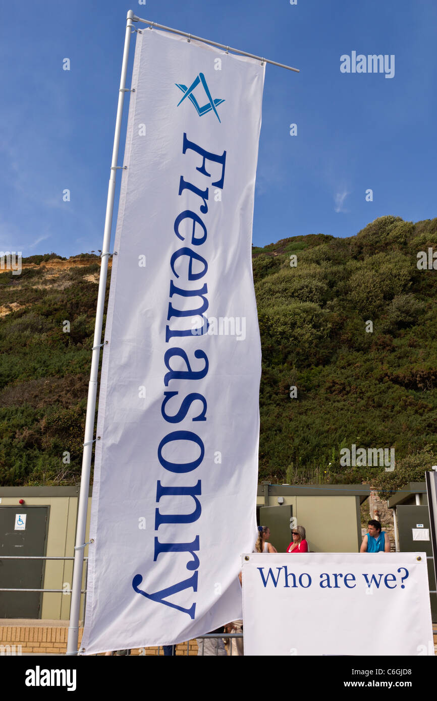 La massoneria Bandiera e 'Chi siamo?' firmare al di fuori di una informazione pubblica stand al festival all'aperto con squadra e compasso logo Foto Stock