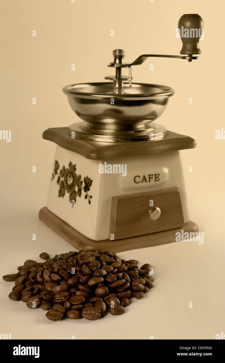 Vintage stilizzata macinino da caffè e un mucchio di chicchi di caffè close-up isolato dai toni seppia Foto Stock