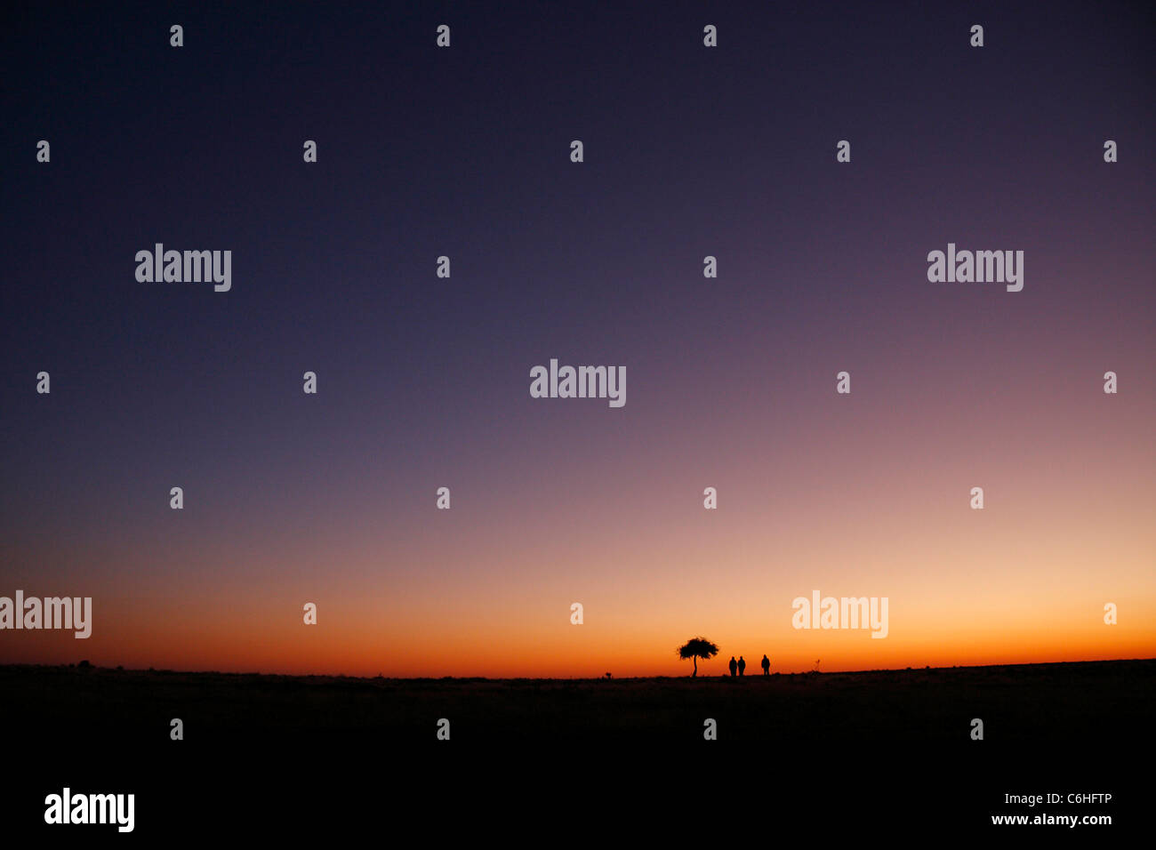 Tre escursionisti stagliano al tramonto nel deserto paesaggio Foto Stock