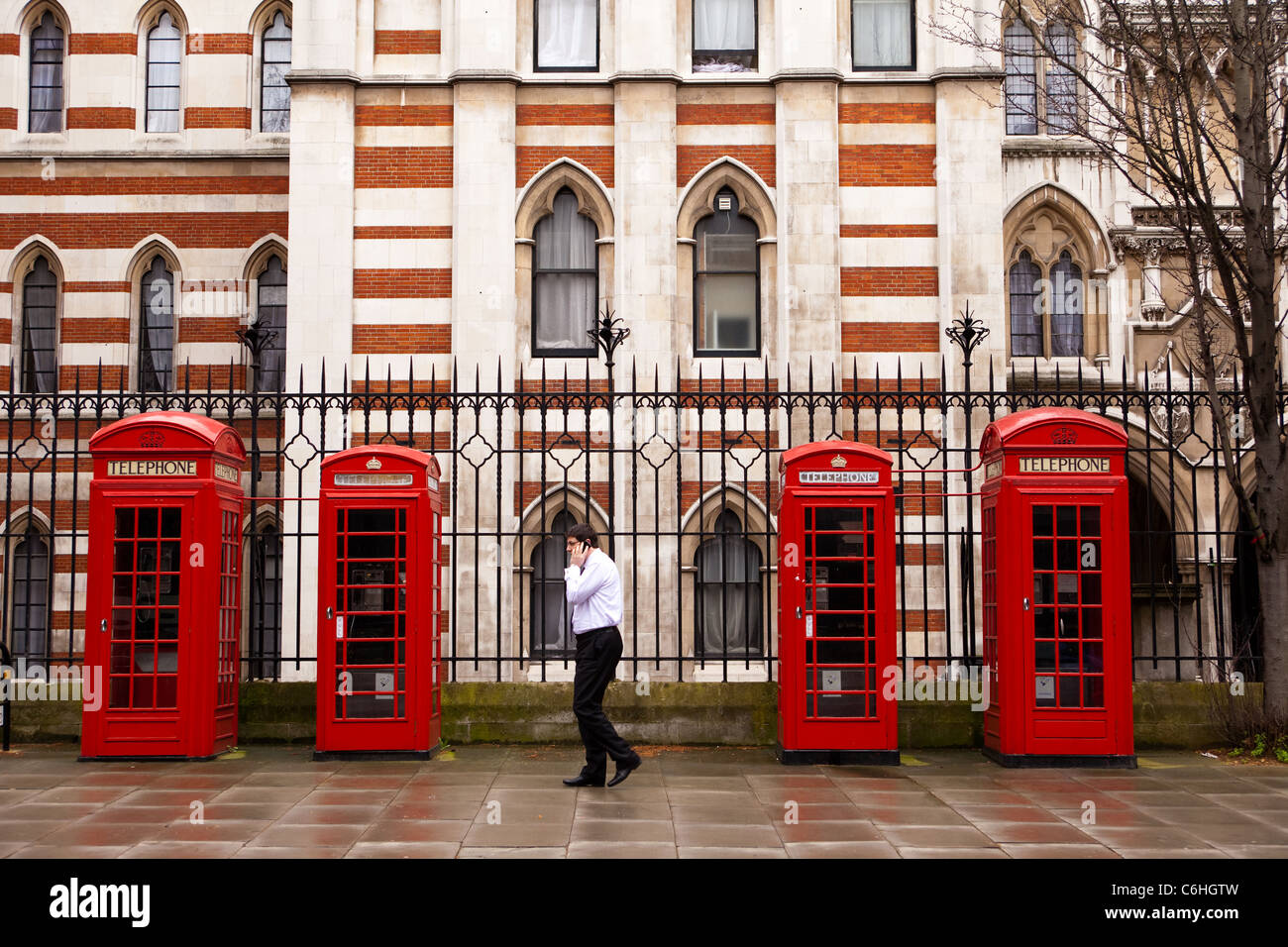 Utente di telefonia mobile accanto al telefono rosso caselle accanto alla High Court, Chancery Lane, Londra Foto Stock