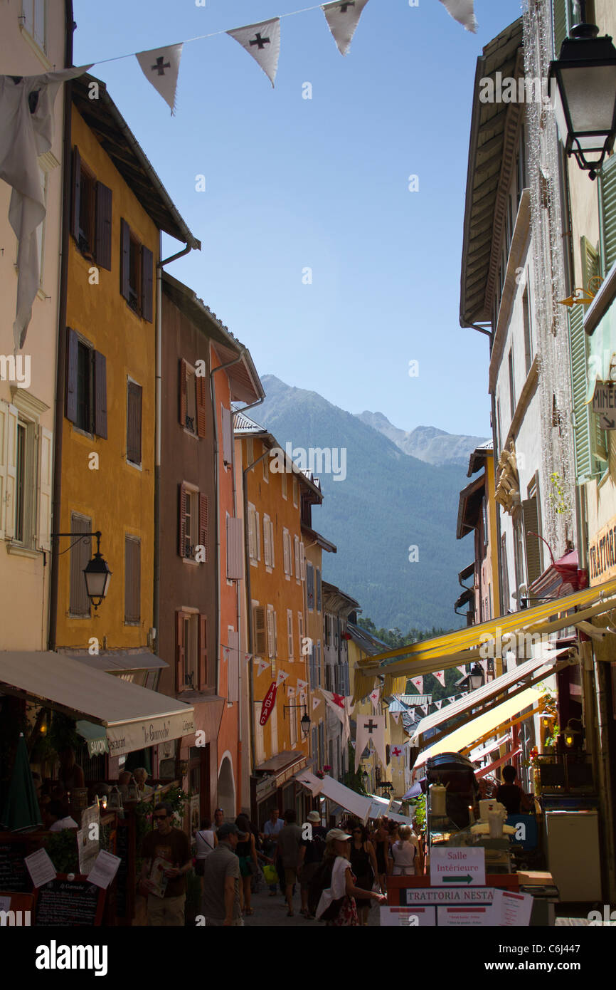 Una strada stretta - Rue de Castres - con negozi e caffetterie nel centro storico di Briançon nelle Alpi francesi in estate Foto Stock