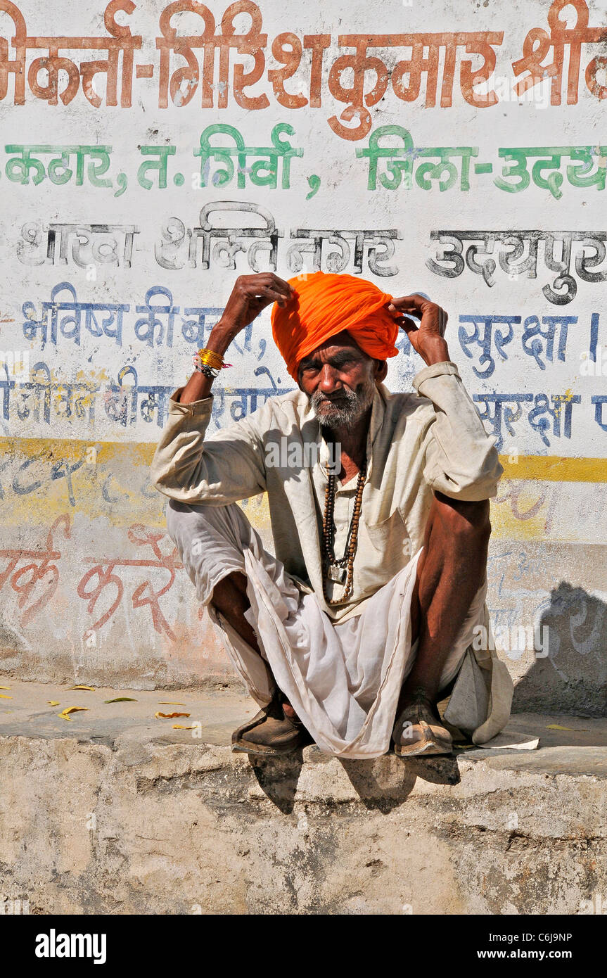 Il vecchio uomo squatting da parete Colli Aravalli Rajasthan in India Foto Stock