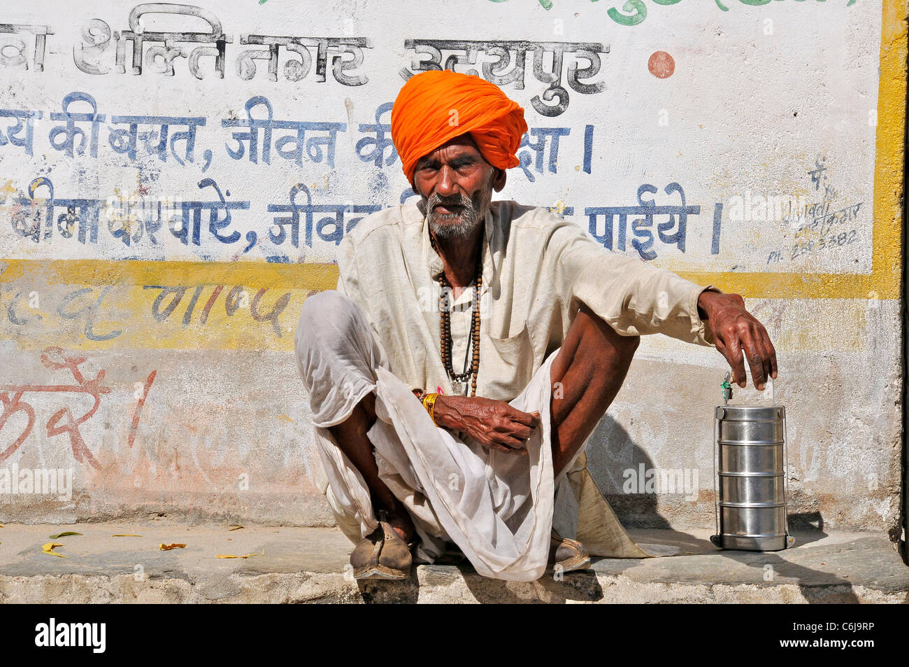 Il vecchio uomo squatting da parete Colli Aravalli Rajasthan in India Foto Stock