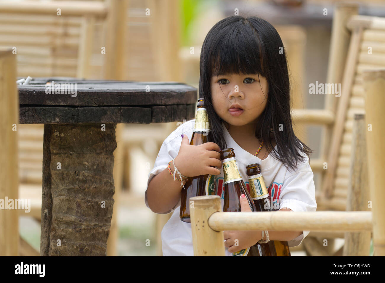 Poco ragazza asiatica che trasportano le bottiglie di birra, Ko Phangan, Thailandia Foto Stock