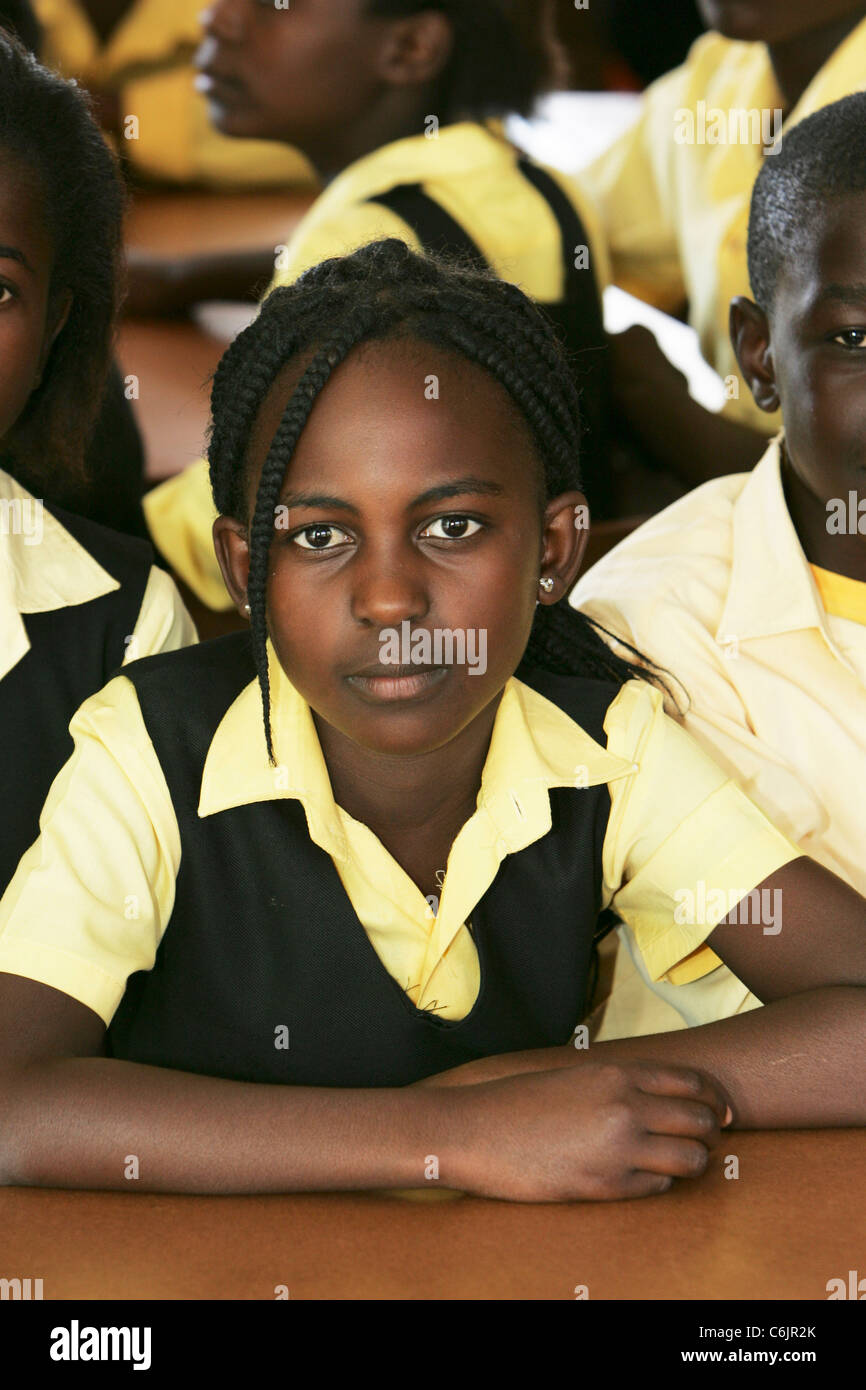 Ritratto di una scuola ragazza seduta alla sua scrivania con altri studenti in background Foto Stock