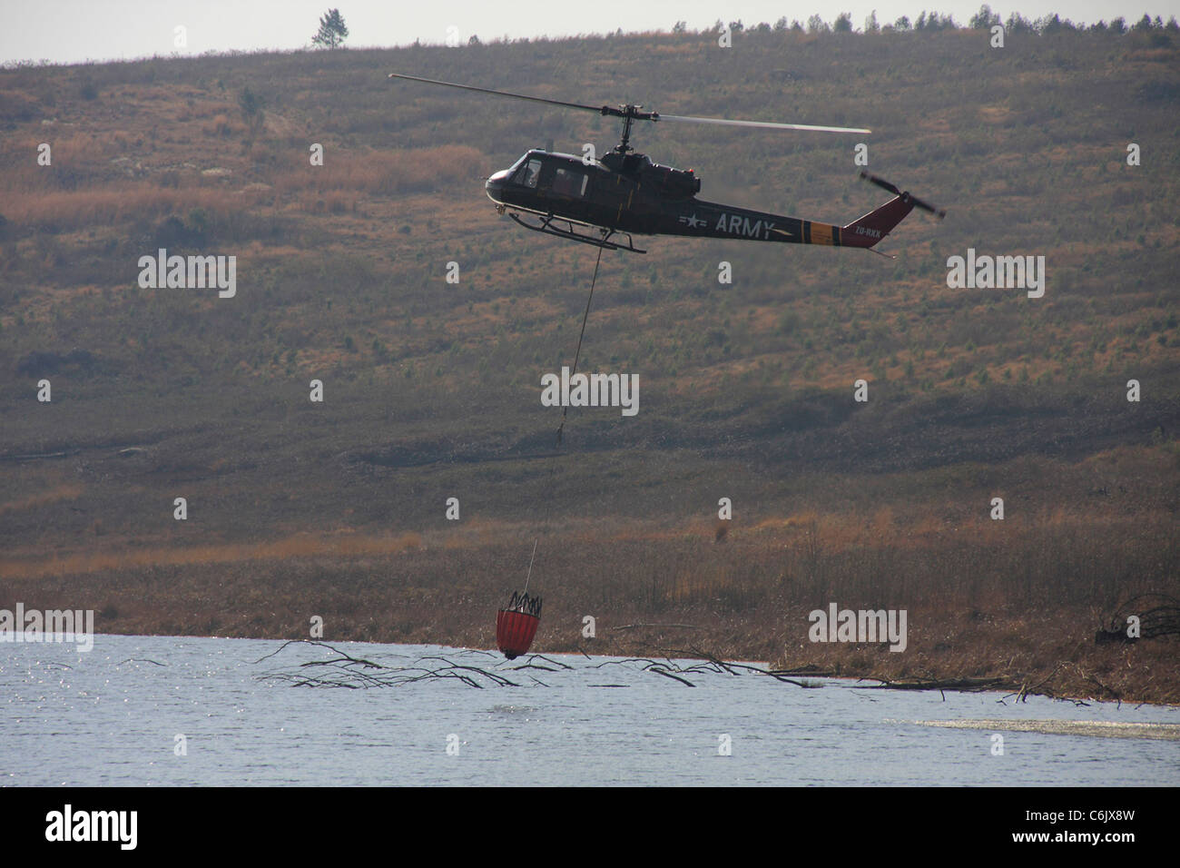 Esercito elicottero raccolta di acqua da una diga Foto Stock