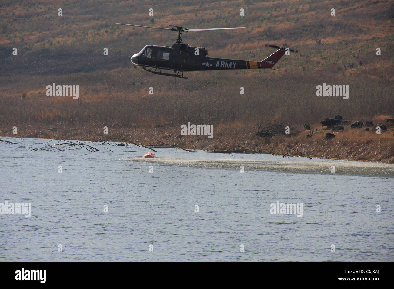 Esercito elicottero raccolta di acqua da una diga Foto Stock
