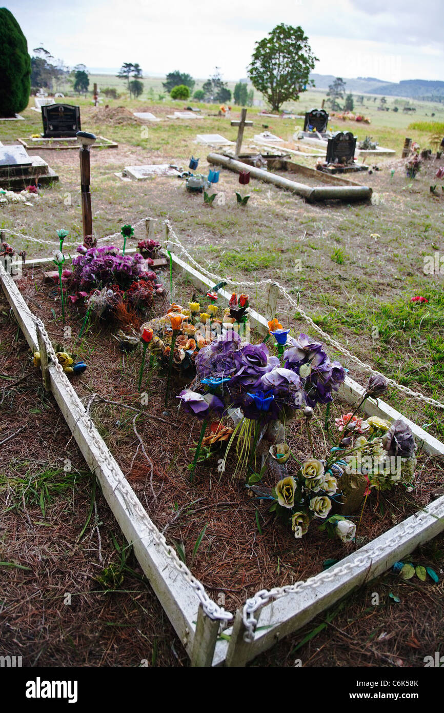 Una vecchia tomba decorata con fiori artificiali. Cimitero, Northland e North Island, Nuova Zelanda. Foto Stock