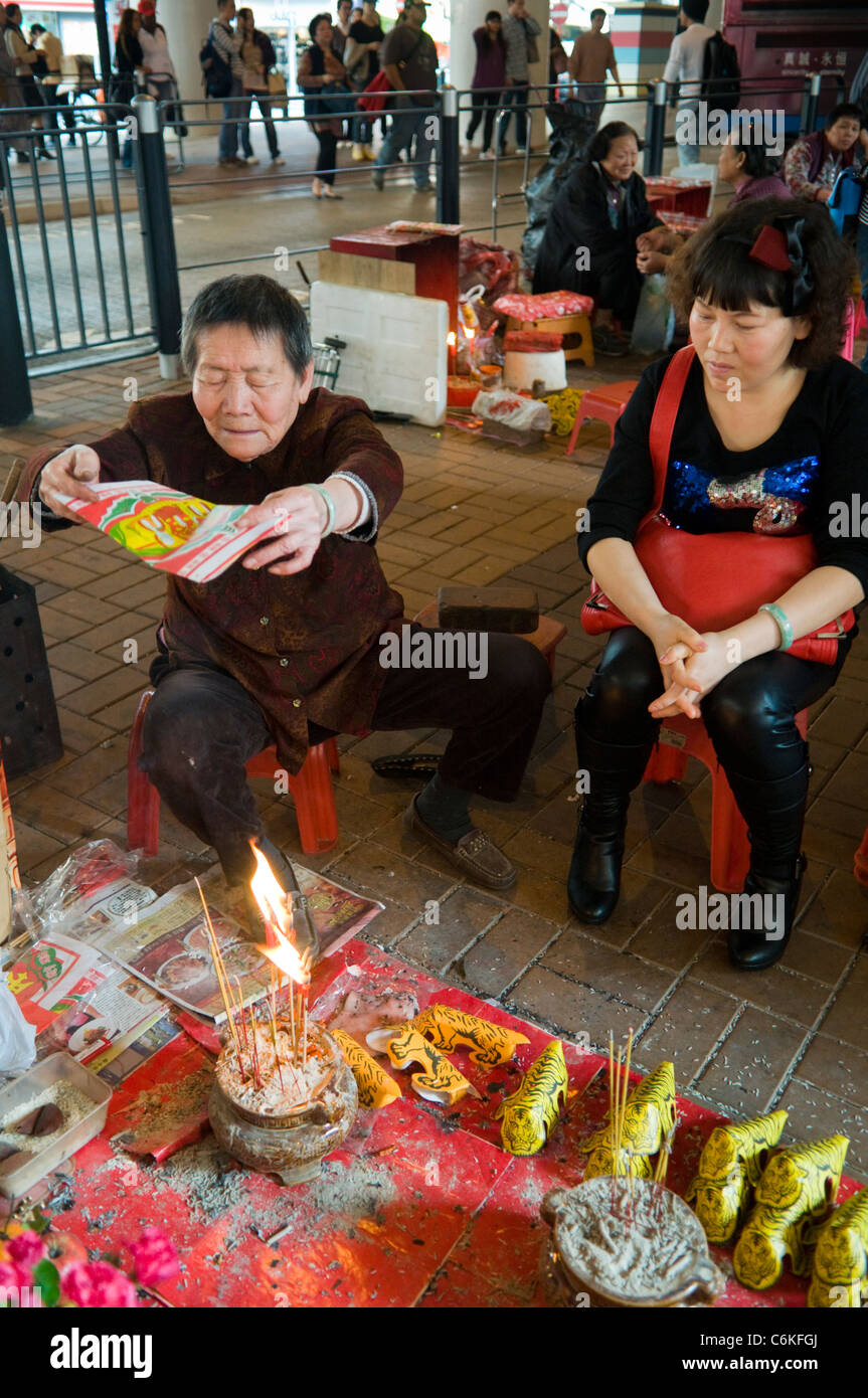 Vecchia donna svolge una buona fortuna rituali sotto il collo d'oca ponte in Causeway Bay Hong Kong Foto Stock