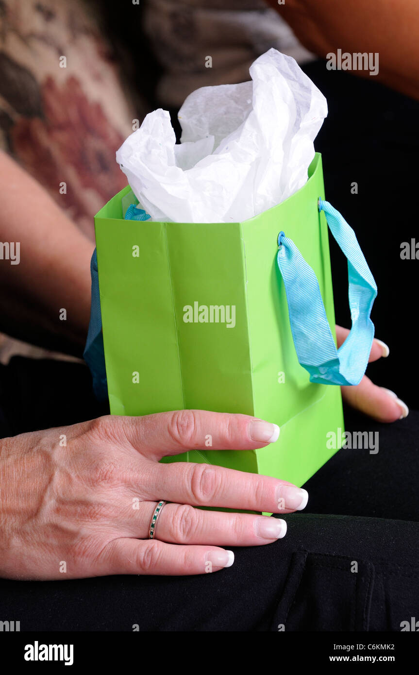 Donna matura le mani tenendo un regalo di compleanno in borsa Foto Stock