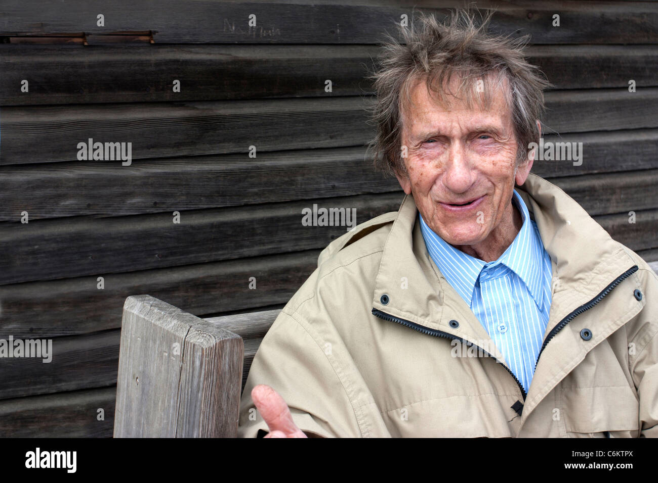 Uomo anziano seduto su una panchina al di fuori di un capannone di aggiudicazione Foto Stock