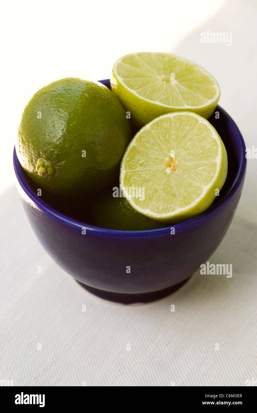 Limes, intero e dimezzato nel recipiente Foto Stock