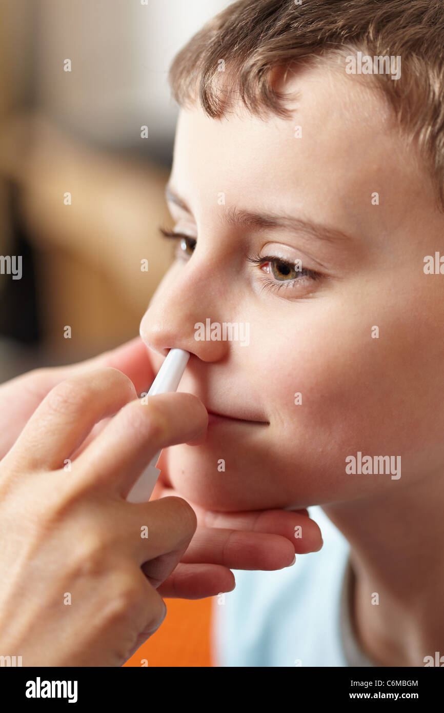 Donna dottore mani dando un ragazzo una dose di spray nasale contro influenza Foto Stock