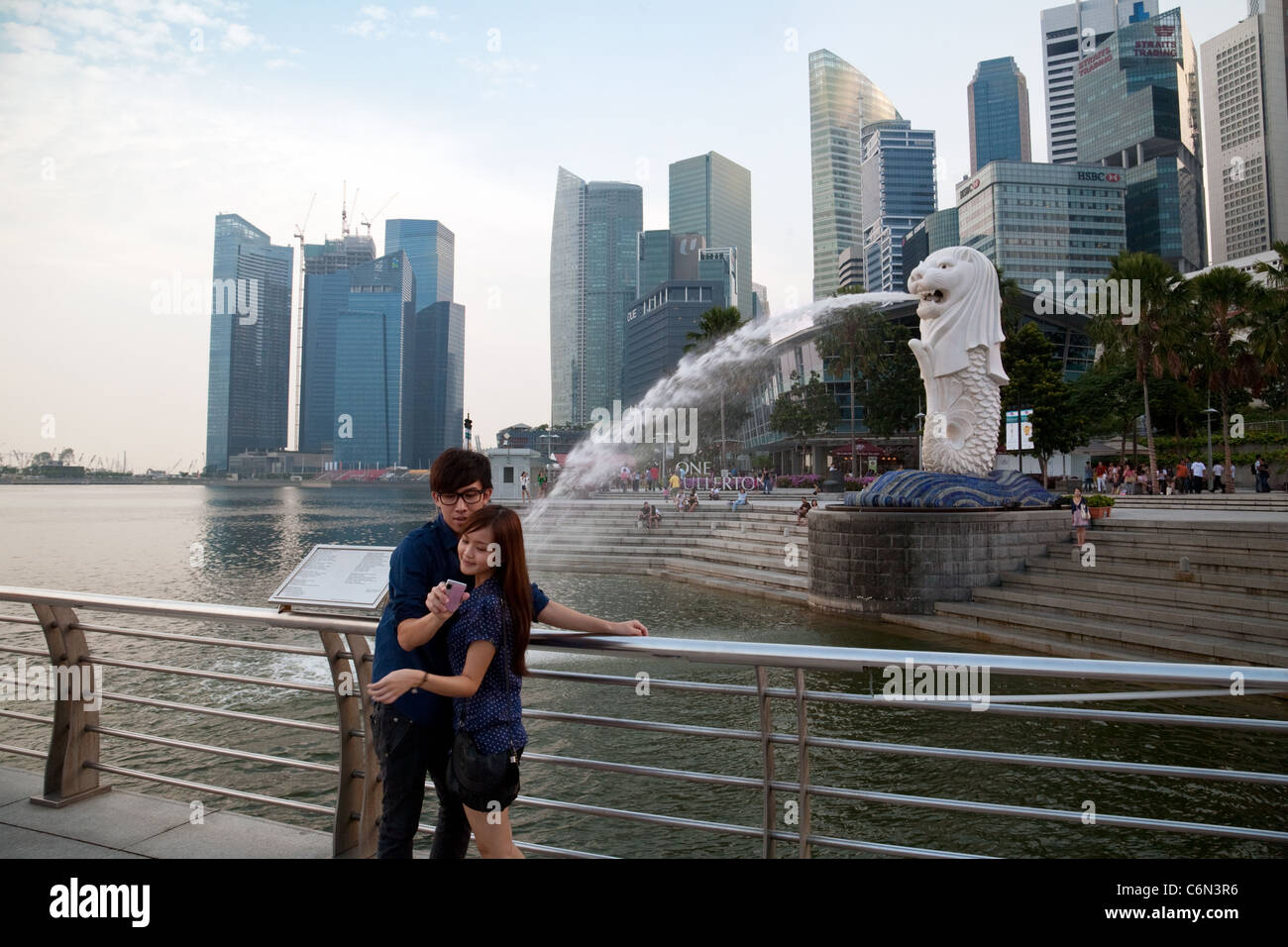 Una coppia di Singapore prendere le loro foto davanti il Merlion, simbolo di Singapore, l'area di Marina Bay, Singapore Asia Foto Stock