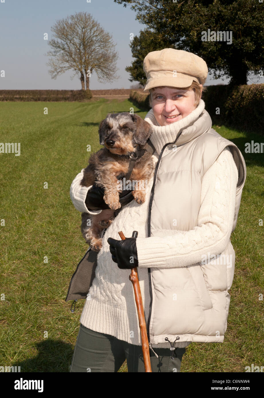 Una giovane donna che mantiene una miniatura Wirehaired cane bassotto in campagna Foto Stock