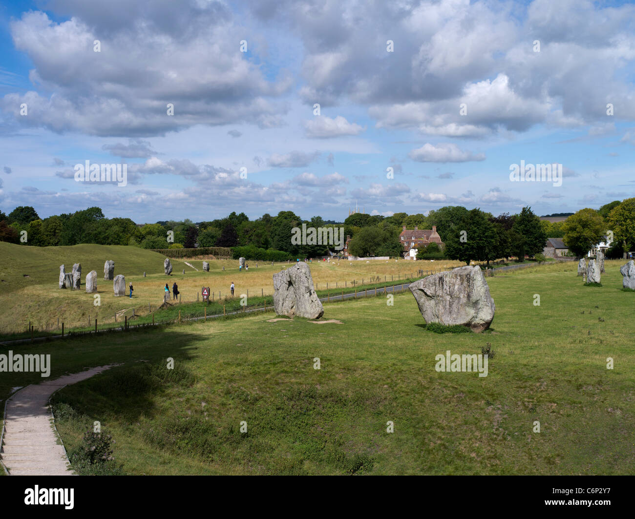 dh Avebury Stone Circle AVEBURY WILTSHIRE turisti intorno alla posizione megalitica cerchio di pietre e case di villaggio età neolitica henge Foto Stock