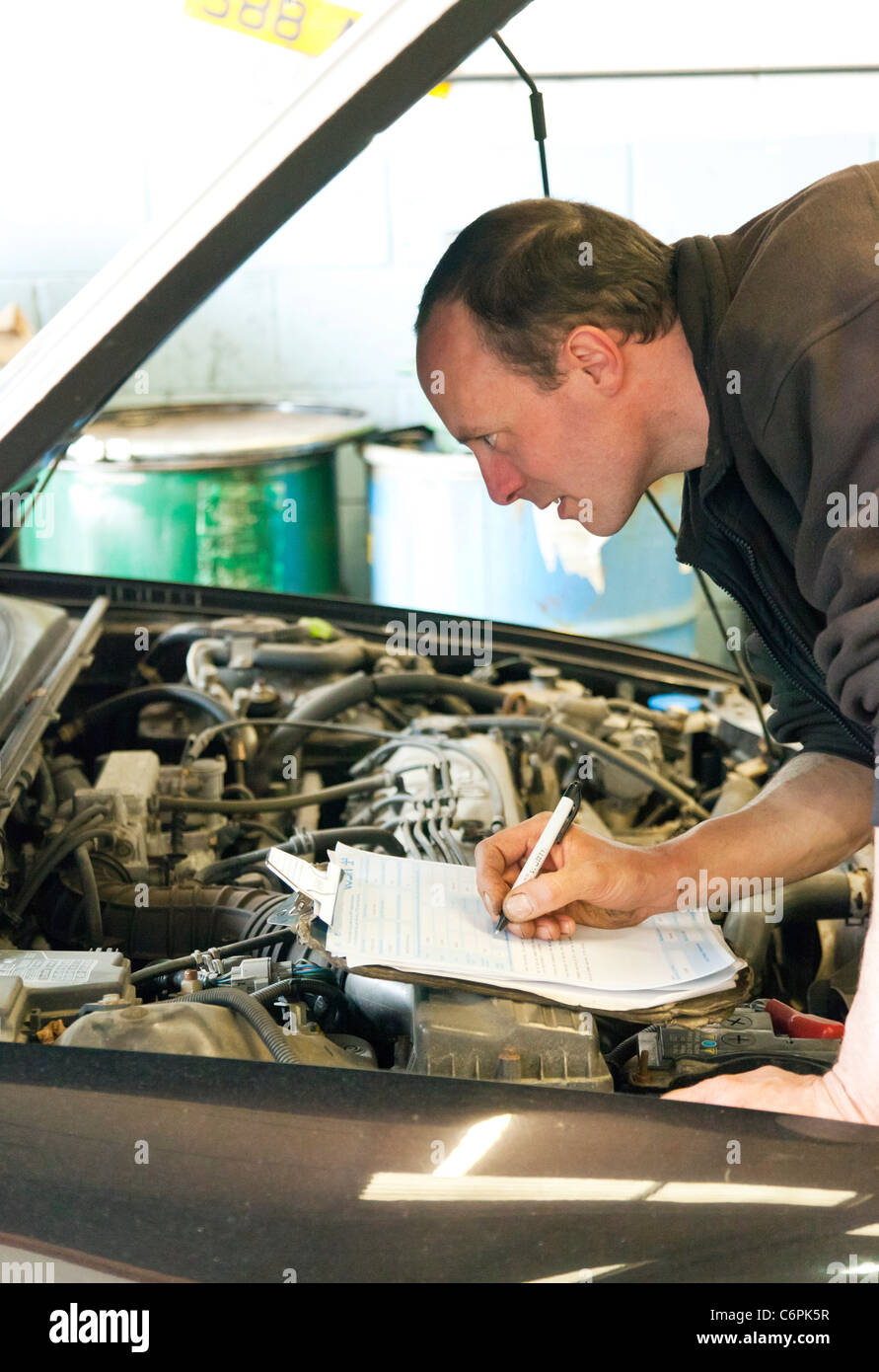 Autofficina controllando la parte inferiore di un auto durante un MOT test nel Regno Unito Foto Stock