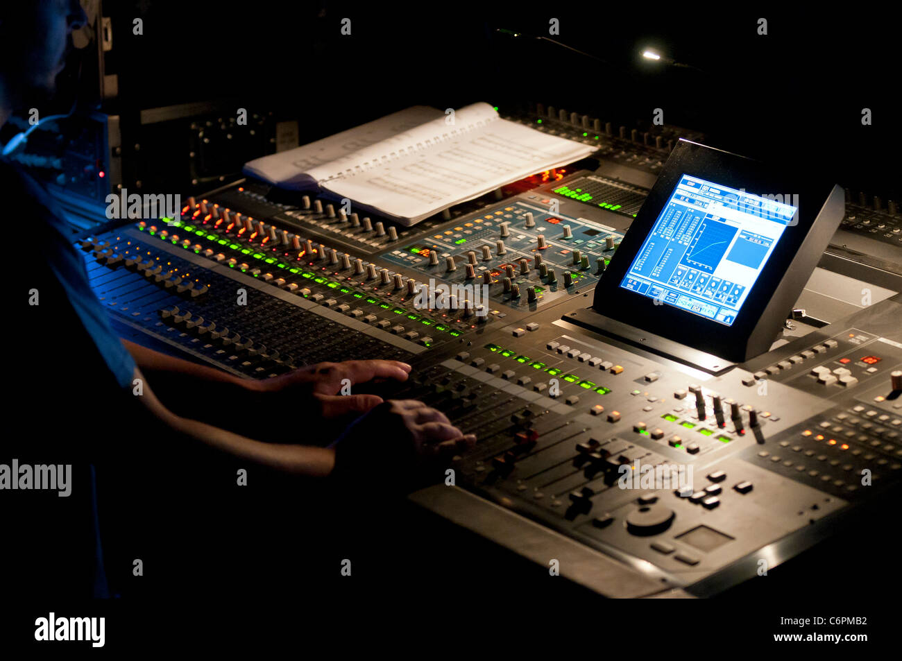 Tecnico audiovisivo il controllo di una console di mixaggio durante uno spettacolo. Foto Stock