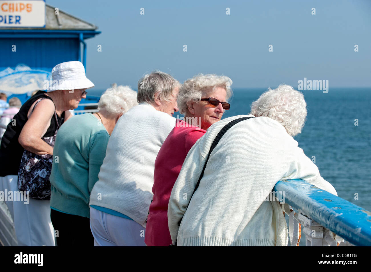 Anziane signore appoggiata sulla ringhiera di Llandudno Pier Foto Stock