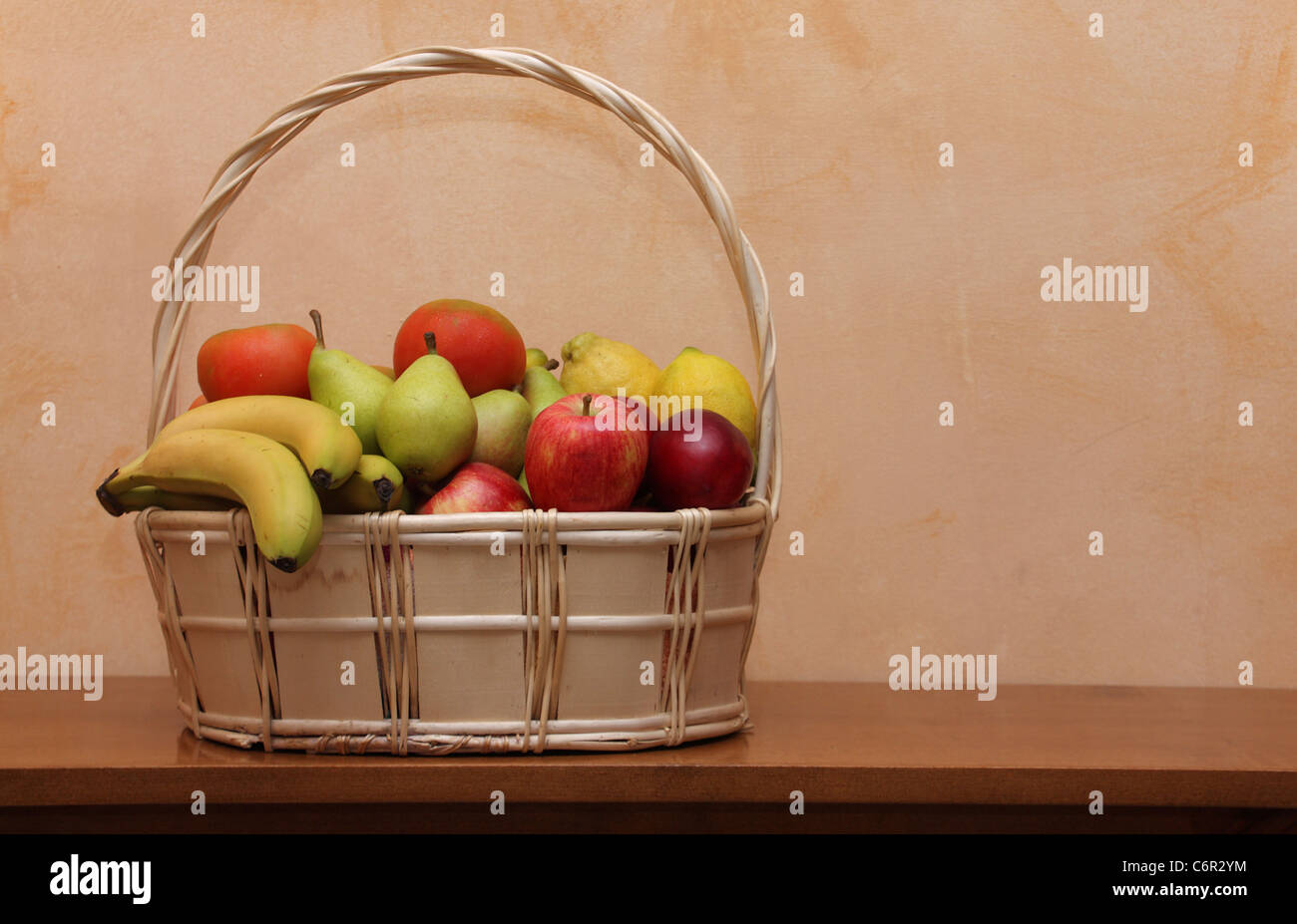 Cesto di vimini con frutta e verdura sulla tavola di legno Foto Stock