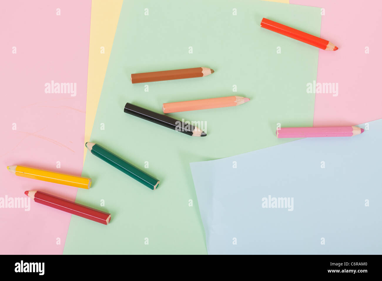 Matite colorate e carte colorate su una scrivania per bambini Foto Stock