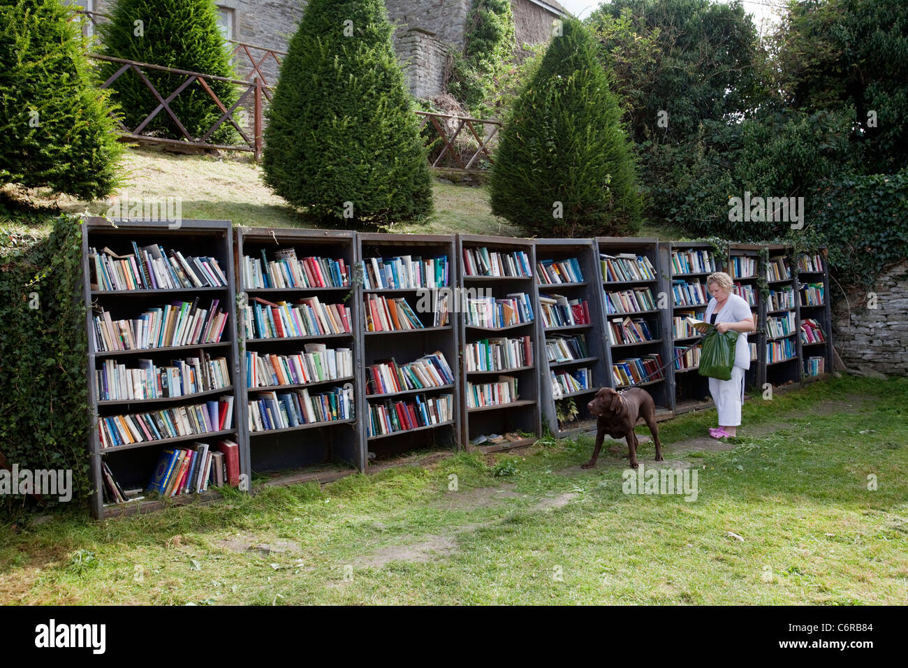 Una donna navigando in un bookshop onestà nel parco del castello di fieno in Hay-On-Wye, Regno Unito Foto Stock