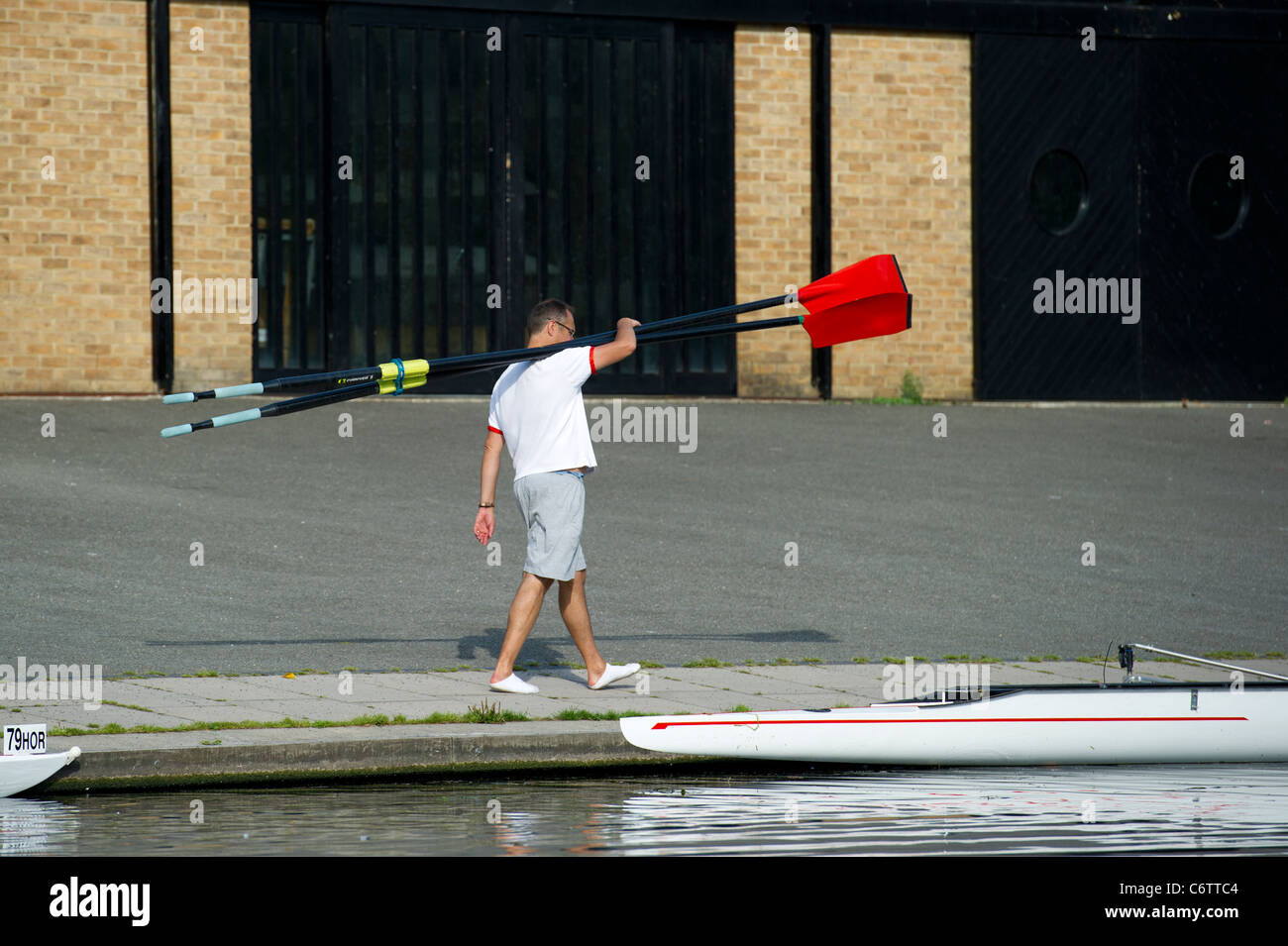 Un uomo che porta i remi per un sedile otto barca a remi lungo il fiume Cam a Cambridge. Foto Stock