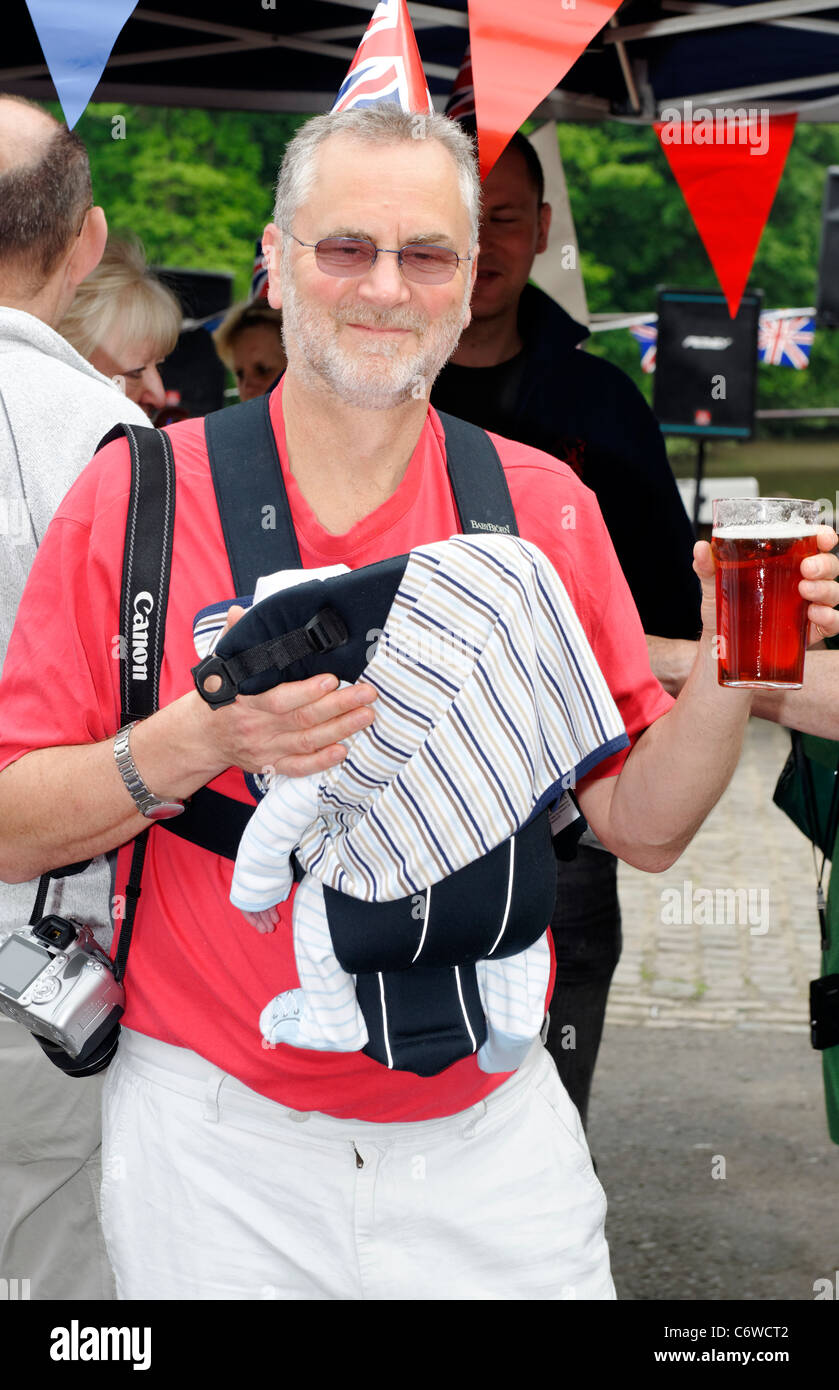 Uomo in possesso di un bambino e una pinta presso il Royal Wedding street party, Isleworth Foto Stock