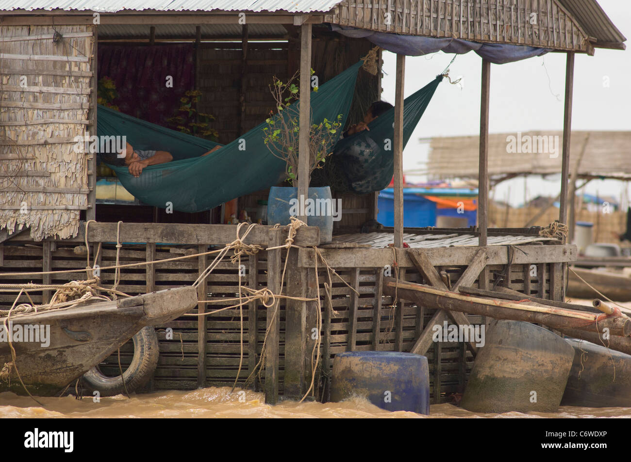 Uomo in un amaca a Kompong Klang villaggio galleggiante, lago Tonle Sap, vicino a Siem Reap, Cambogia Foto Stock