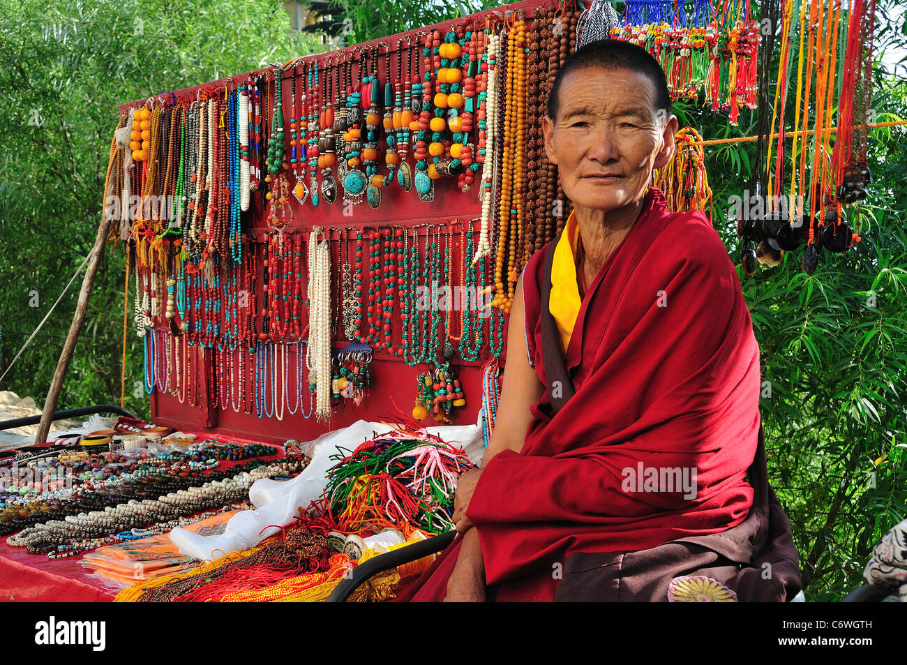 Donna tibetana tradizionale di vendita accessori tibetano sulla strada. Foto Stock