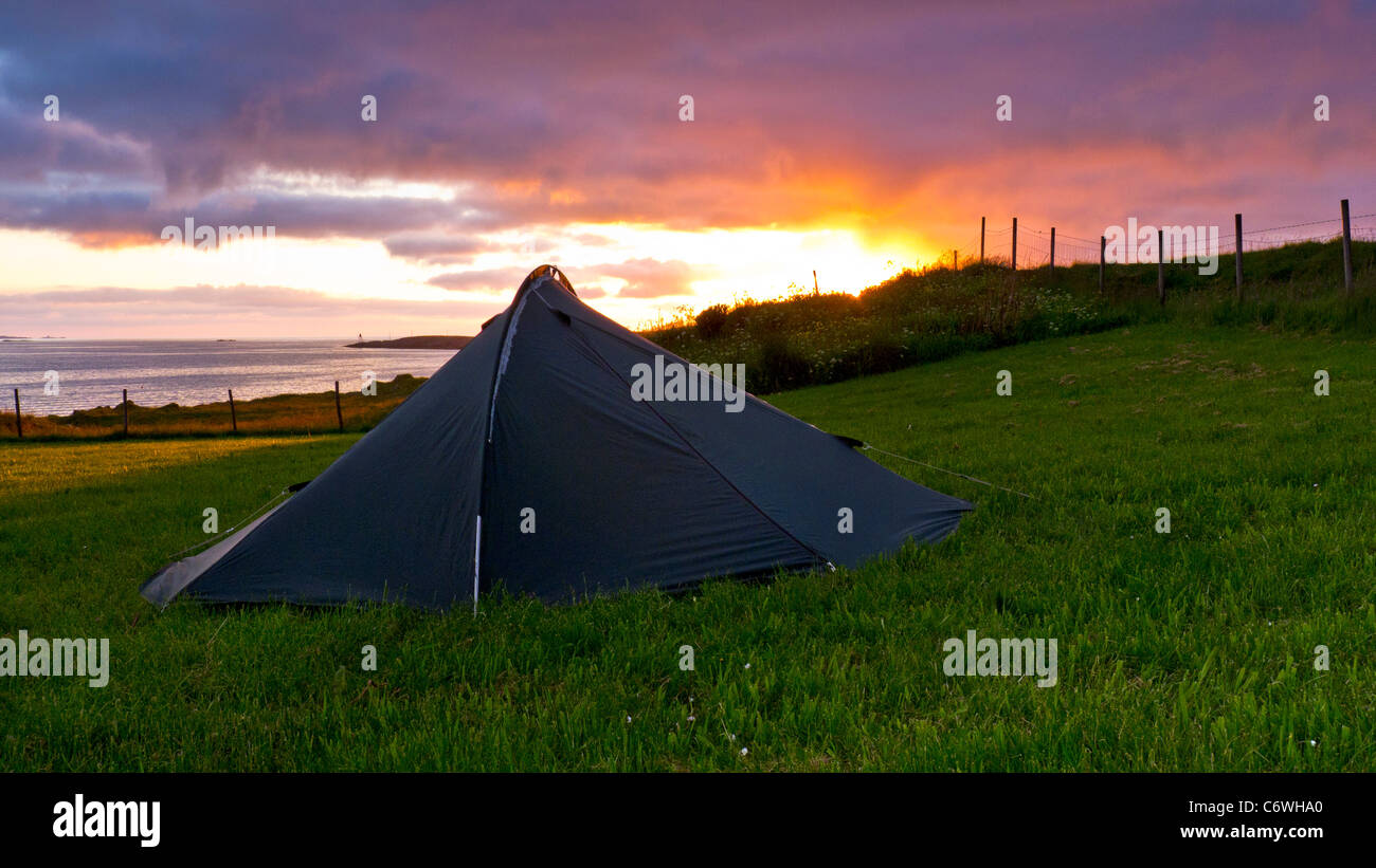 Una piccola tenda campeggio in un campo da un fiordo al tramonto, Haugesund, Norvegia Foto Stock