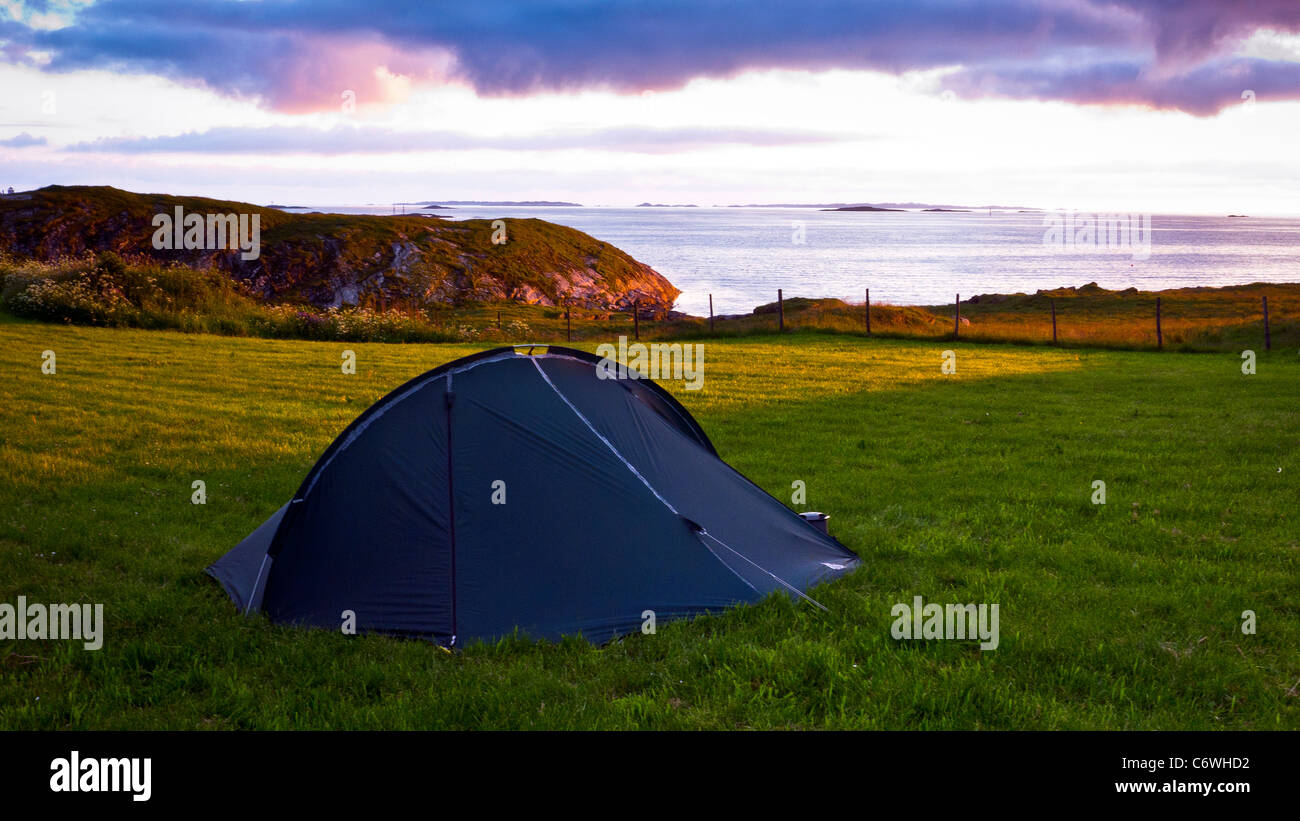 Una piccola tenda campeggio in un campo da un fiordo al tramonto, Haugesund, Norvegia Foto Stock