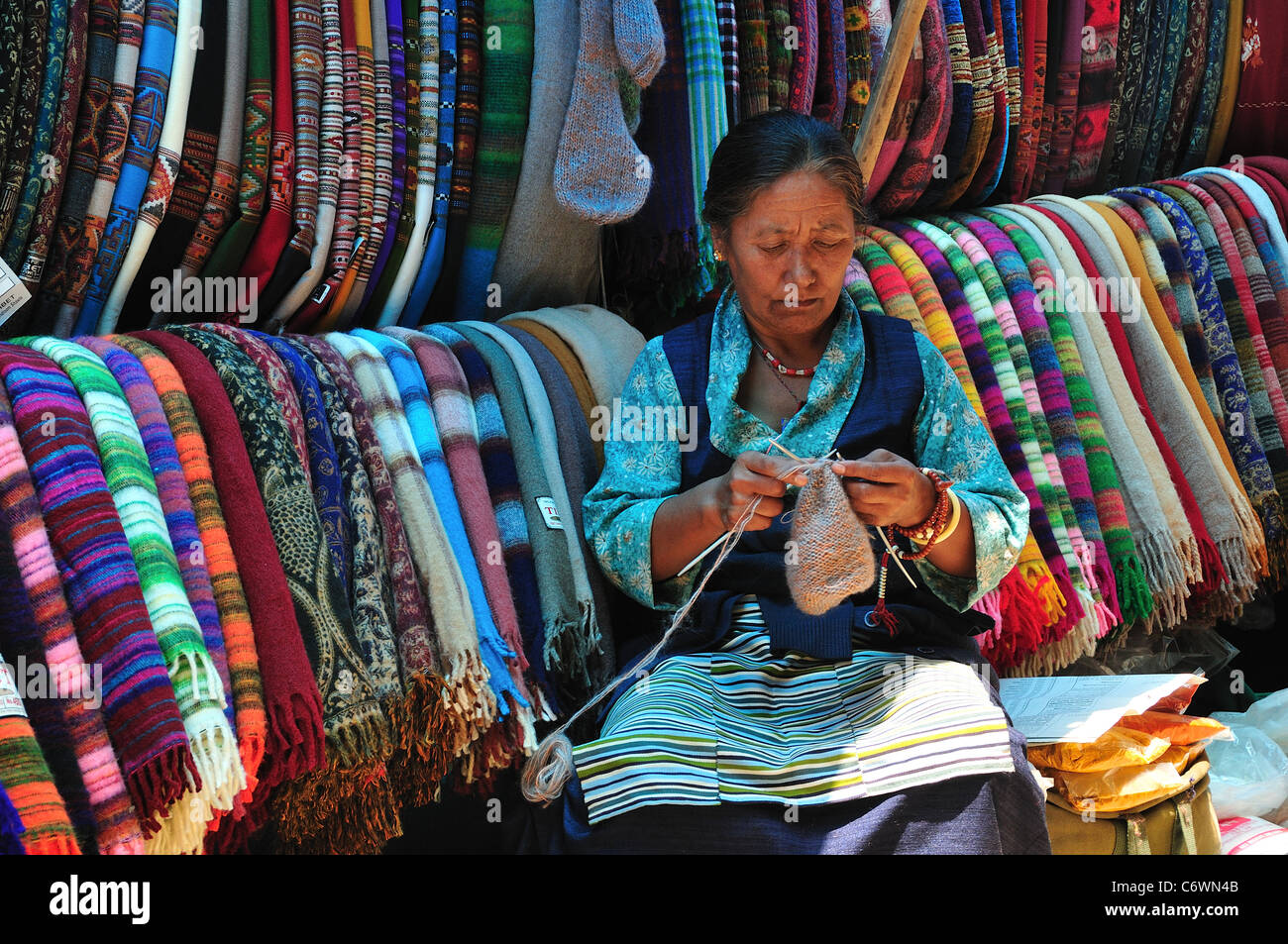 Il Tibetano donna vendita worm colorati scialli sulla principale strada dello shopping. Foto Stock