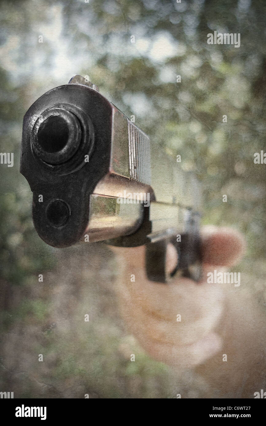Mano che tiene una pistola fumante Foto Stock