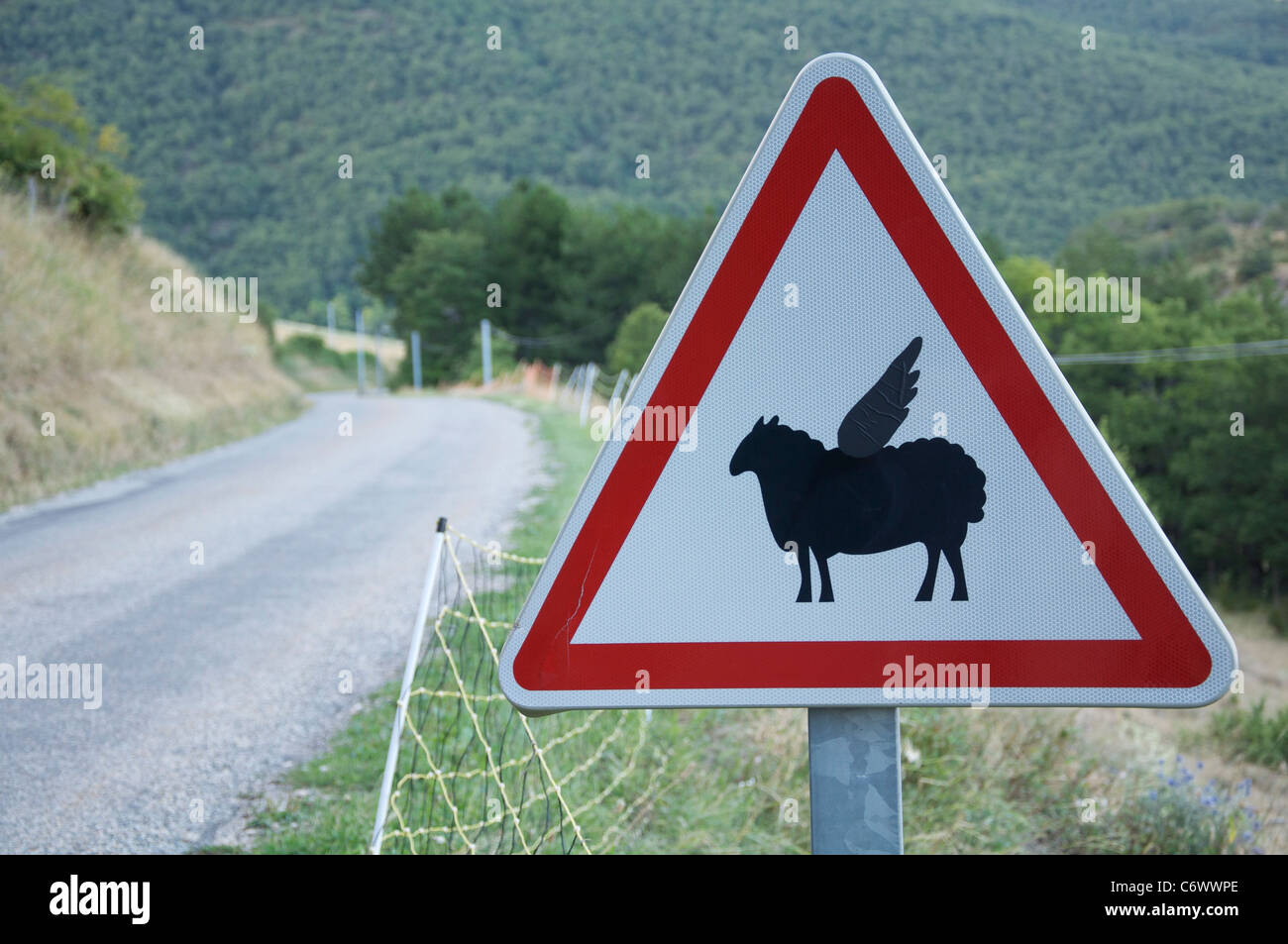 Attenzione, bassa battenti pecora! Questo ambiente rurale francese cartello stradale è stata modificata dal divertente aggiunta di ali per il simbolo di pecora. La Drôme, Francia. Foto Stock