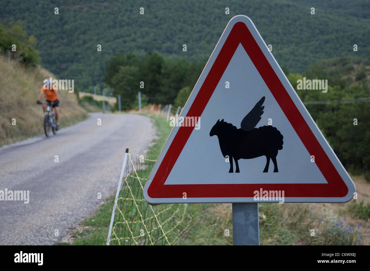Attenzione, bassa battenti pecora! Questo ambiente rurale francese cartello stradale è stata modificata dal divertente aggiunta di ali per il simbolo di pecora. La Drôme, Francia. Foto Stock