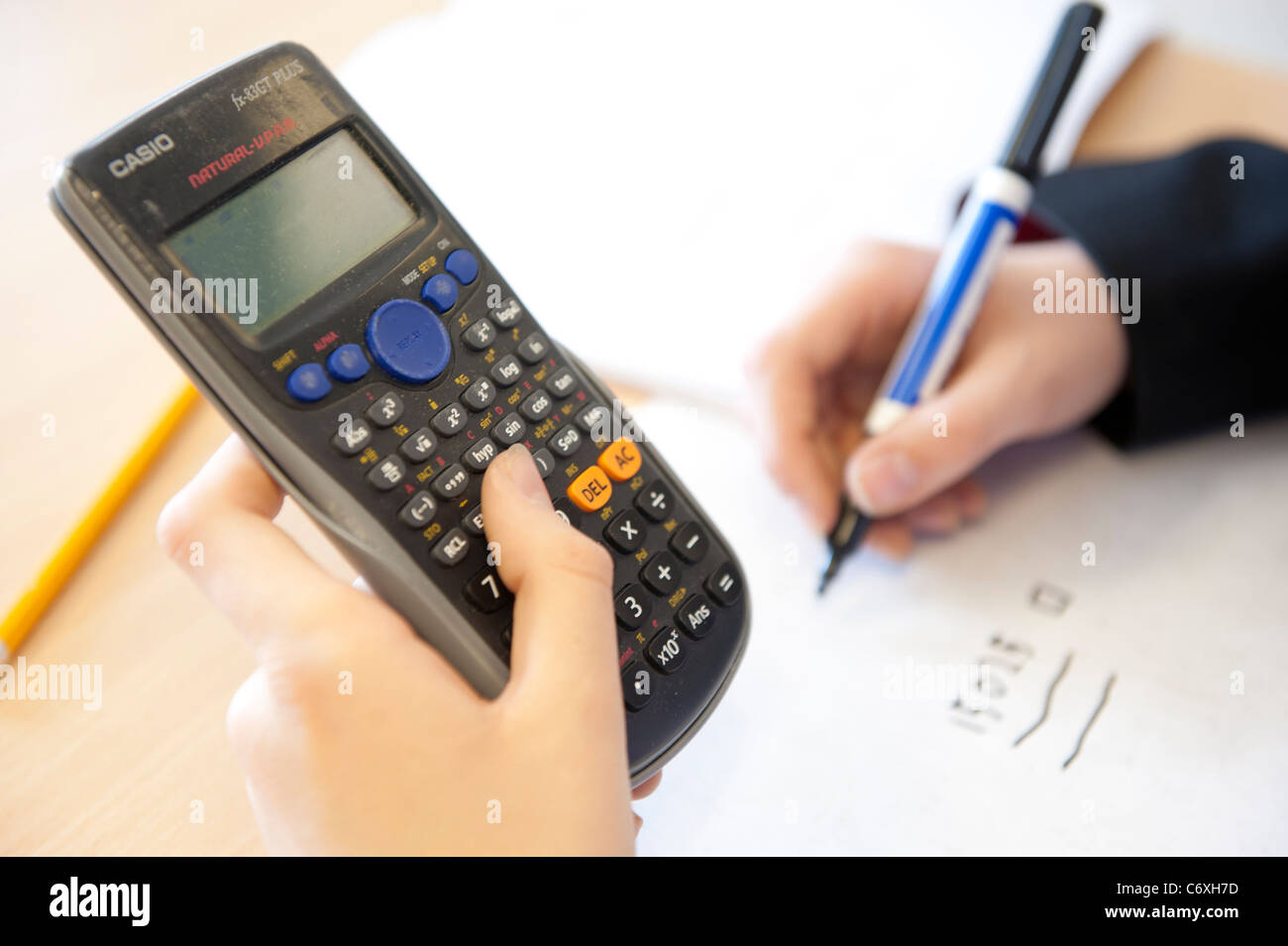 Un allievo lavora fuori un problema di matematica utilizzando una calcolatrice. Foto Stock