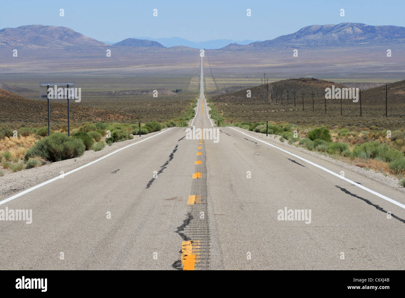 Lonely Highway 6 in Nevada si estende su un ampia valle in una linea retta con ondulazioni di calore a distanza Foto Stock
