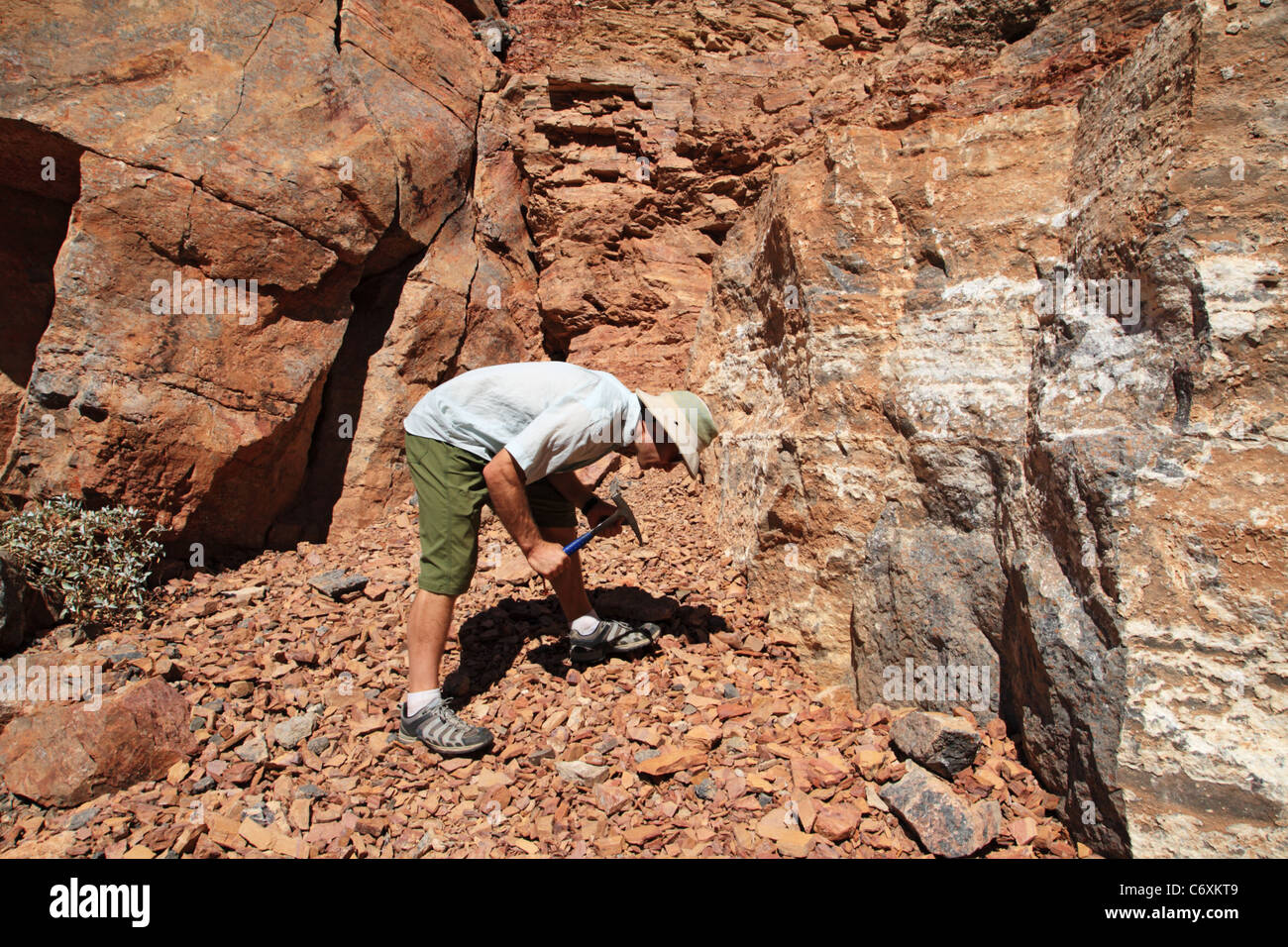 Un uomo rockhounding in corrispondenza di un affioramento di roccia con martello Foto Stock