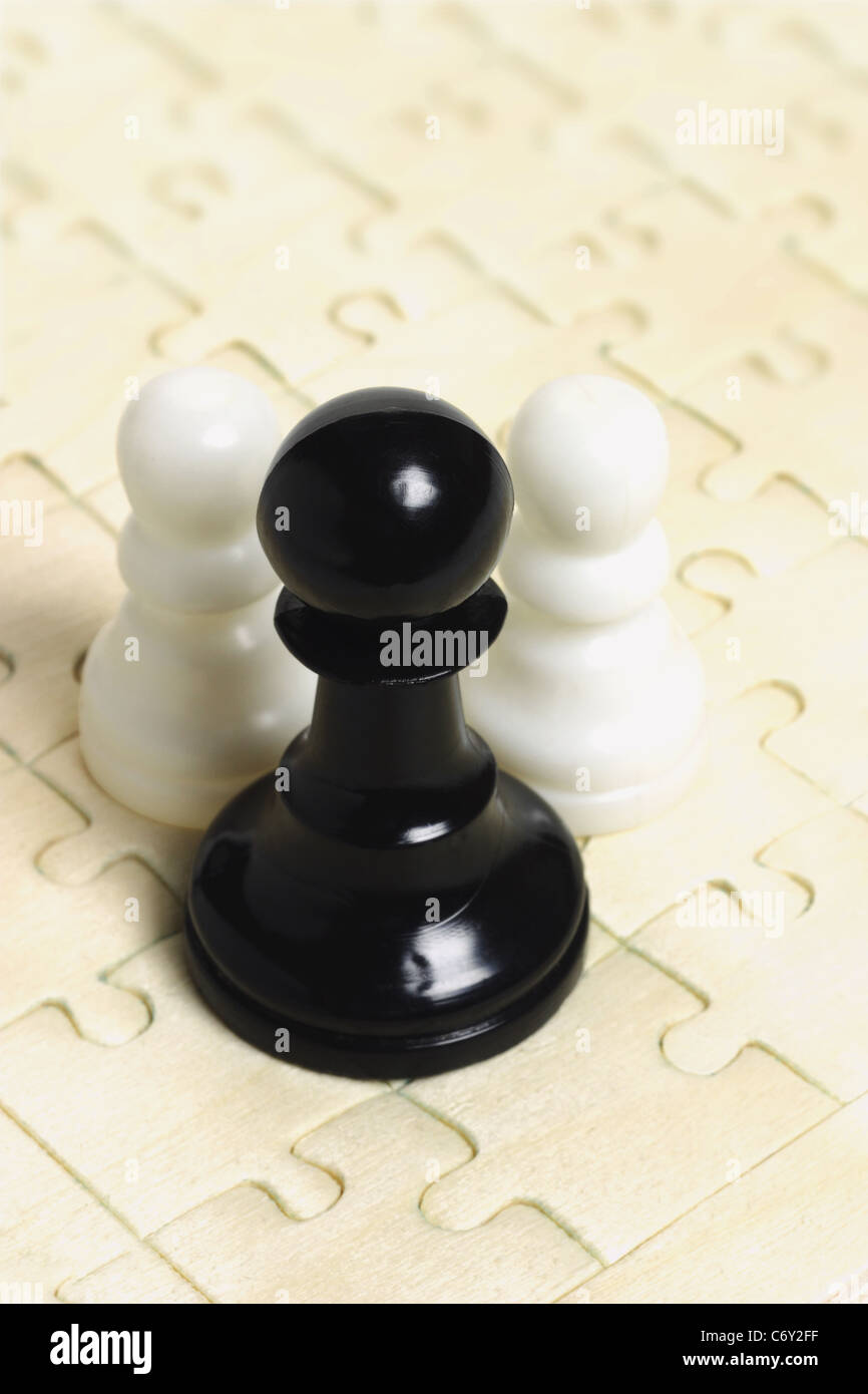 In bianco e nero a scacchi pegni su puzzle sullo sfondo Foto Stock