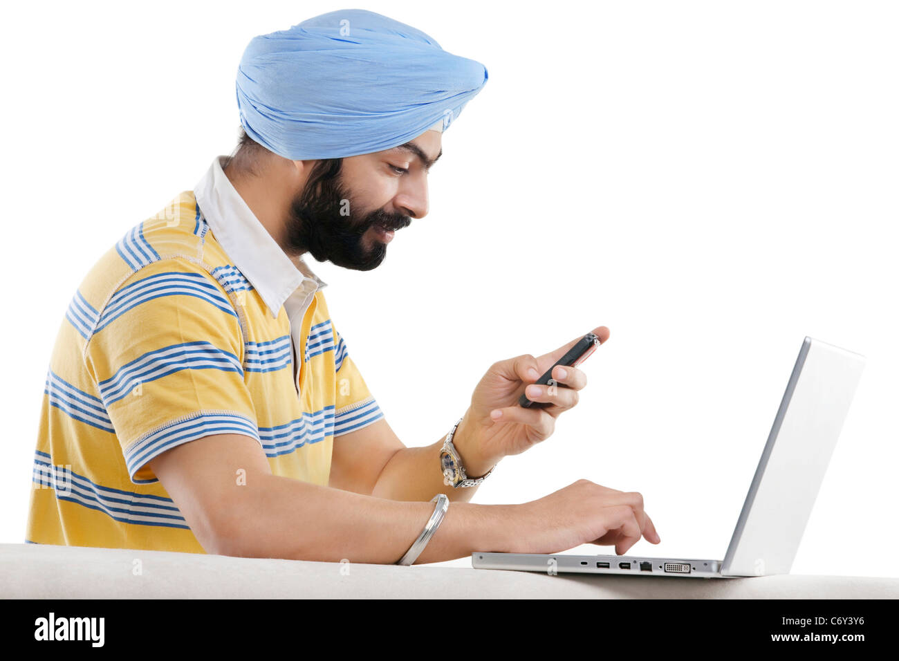 La religione sikh uomo con un telefono cellulare e un pc portatile Foto Stock