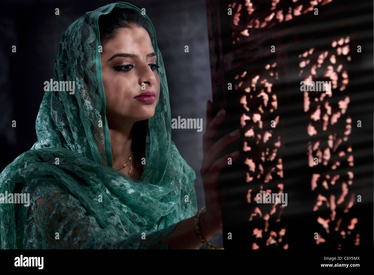 Donna musulmana guardando fuori della finestra Foto Stock