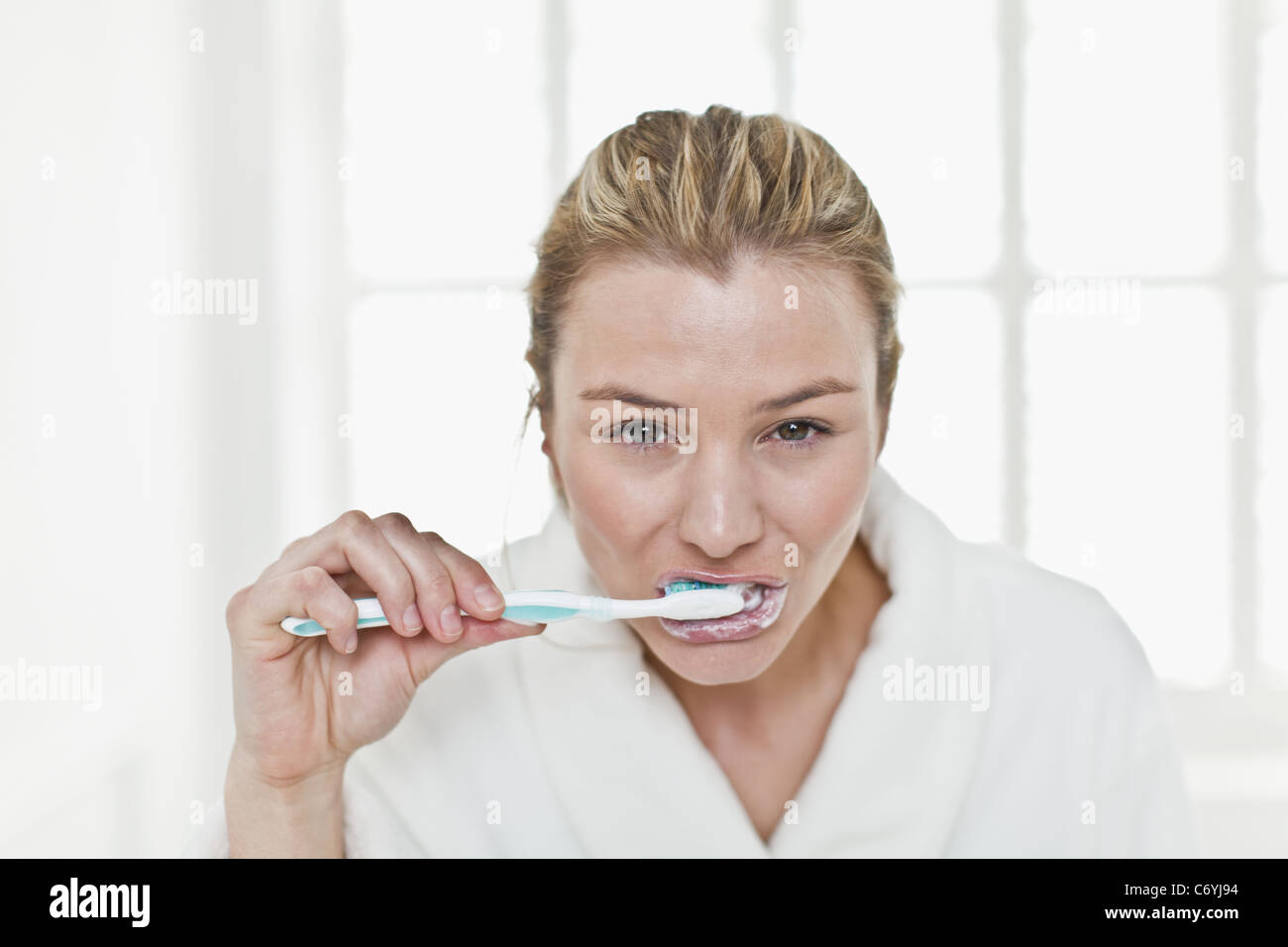 Donna spazzolare i suoi denti nella stanza da bagno Foto Stock
