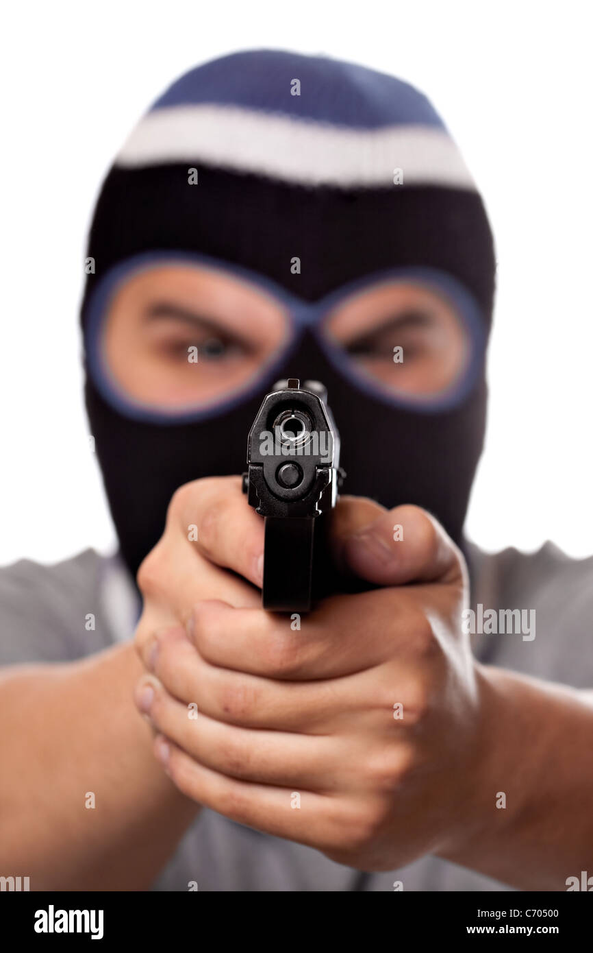 Un arrabbiato cerca uomo che indossa una maschera da sci puntando una pistola nera al visualizzatore. Profondità di campo. Foto Stock